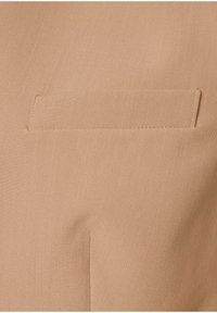 Tissu beige avec une poche passepoil horizontale unique présentant des bords cousus, centrée sur l'image.
