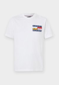 Witte katoenen t-shirt met een kleurrijk gedrukt logo op de linkerborst, met blauwe, gele, rode en witte geometrische vormen. Korte mouwen.