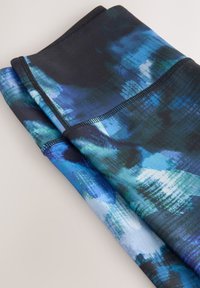 Dos telas dobladas en varios tonos de azul con patrones abstractos. La textura parece suave, con costuras negras a lo largo de los bordes.