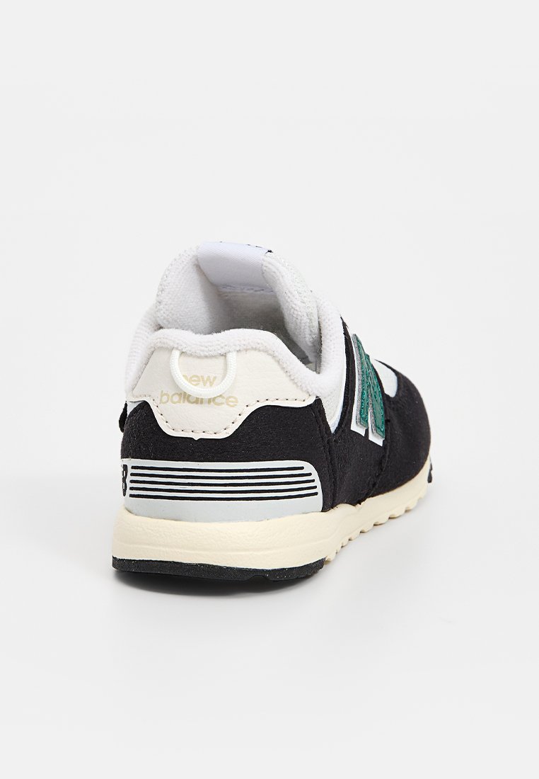 Baskets en suède noir avec accents blancs, col rembourré et logo vert. Présente un bout texturé et une semelle couleur crème avec des rayures noires.