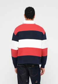 Gestreepte sweatshirt voor heren in rood, wit en marineblauw. Heeft een kraag en lange mouwen; gemaakt van een gladde, gestructureerde stof.