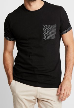 T-shirt nera in cotone con tasca a motivo e bordi a contrasto sulle maniche corte. Vestibilità standard con scollo rotondo.