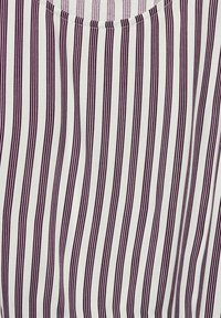 T-shirt à manches courtes en tissu léger avec des rayures verticales étroites violettes sur un fond blanc ; décolleté rond.