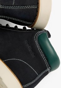 Stivali alla caviglia in suede nero con dettagli in pelle verde, cuciture bianche e suola in gomma beige. Presenta il logo "NeroGiardini."
