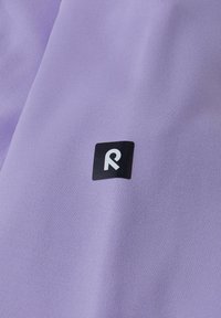 Jasnofioletowa tkanina o gładkiej fakturze z małym czarnym kwadratowym logo z białym "R" w centrum.