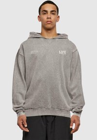 Šedá mikina s kapucí, volného střihu, texturovaná látka a bílý potisk "LIFE" na hrudi. Ribbené manžety a lem.