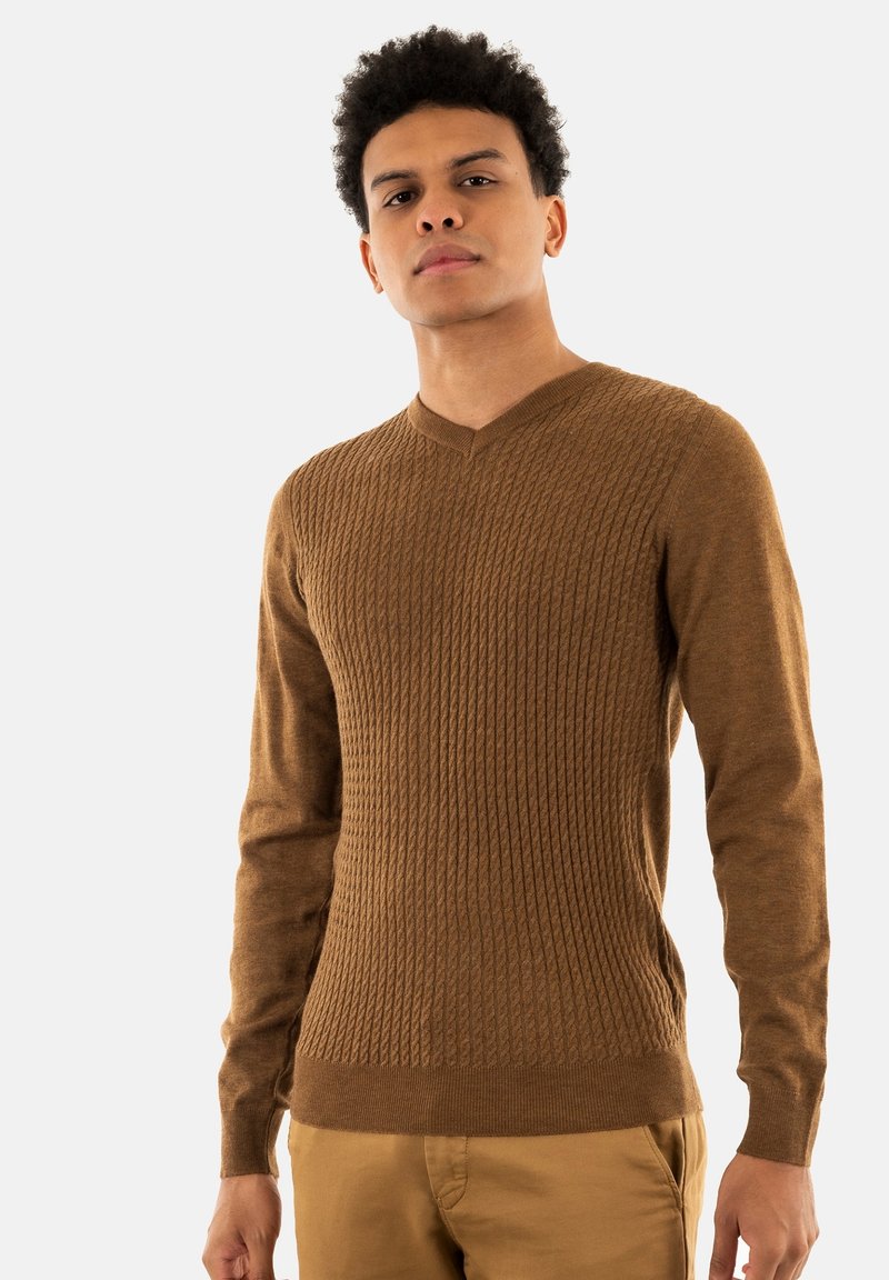 Maglione marrone a coste in morbido filato con scollatura a V, maniche lunghe e design aderente, abbinato a pantaloni chiari.