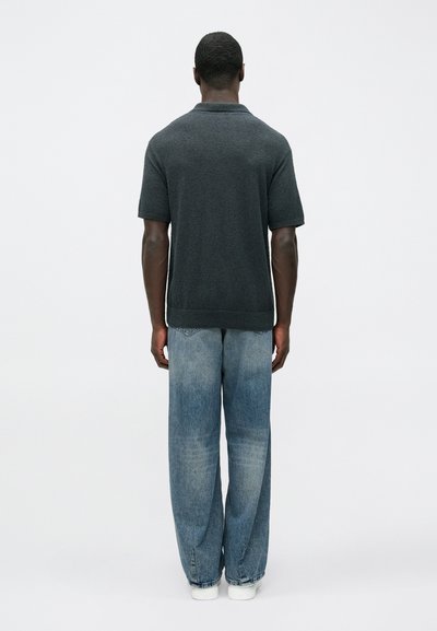 Σκούρο γκρι πόλο μπλουζάκι με κοντά μανίκια, υφή υλικού, άνετη γραμμή. Συνδυασμένο με ανοιχτό μπλε, φαρδιά τζιν και λευκά αθλητικά παπούτσια.