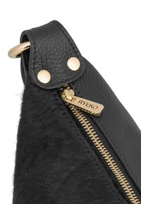 Borsa nera in pelle con una combinazione di pelle testurizzata e tessuto peloso. Cerniera dorata con tirazip brandizzato e dettagli in metallo.