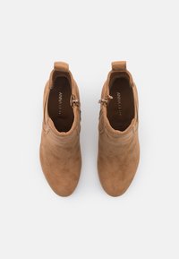 Ruskeat mokkanahkaiset nilkkurit sileällä viimeistelyllä, joissa on sivuvetoketju ja kevyt korko. Yksinkertainen muotoilu, pyöreä kärki ja vetolenkki.