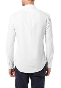 Weißes Langarmhemd mit abgerundetem Saum und einer einzelnen Rückenfalte. Glatte Textur, Knopfmanschetten und ein kleines Kragen-Detail.