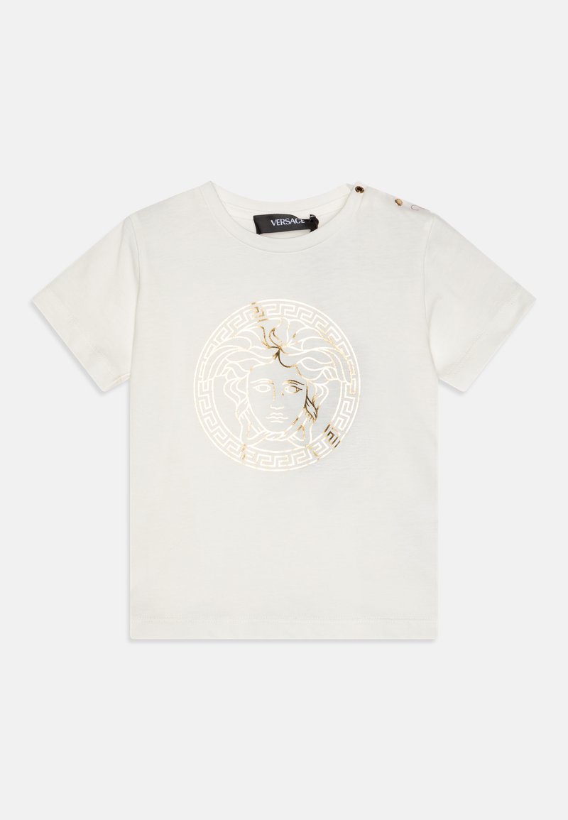 White cotton t-shirt featuring a gold Medusa emblem and Greek key pattern. Short sleeves and two decorative buttons on the shoulder.