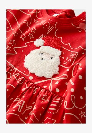 Robe en coton rouge avec un visage de Santa texturé en blanc portant un chapeau rouge, sur un fond de motifs et designs festifs blancs.
