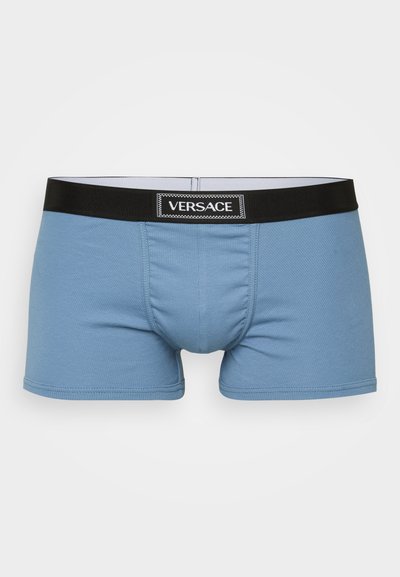 Boxer shorts de algodão azul claro com uma cintura preta que apresenta o logótipo branco "Versace". O tecido tem uma textura canelada e um ajuste justo.