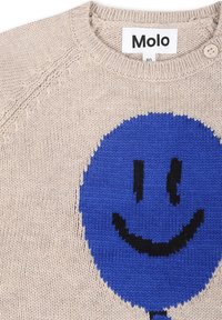 Maglione lavorato a maglia beige con una grande grafica di faccina sorridente blu, forma tondeggiante, dettagli neri e un bottone sulla spalla.