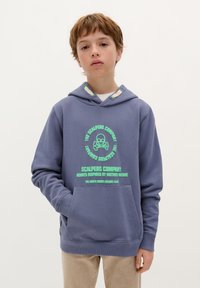 Jasnoniebieska bluza z kapturem z bawełny, z przednią kieszenią, z zielonymi grafikami i wzorem czaszki. Miękka struktura, luźny krój.