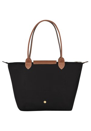 Zwarte tote bag met bruine leren handvatten en details, gouden knoopsluiting en ritssluiting bovenop tegen een witte achtergrond.