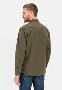 Olijfgroene, lange mouwen shirt van een gladde stof; heeft knoopmanchetten en een klassieke kraag, met een relaxte pasvorm en zonder patronen.