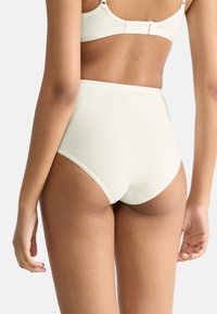 Sous-vêtements taille haute de couleur crème claire, avec une texture lisse, une ceinture subtile et un design minimaliste.