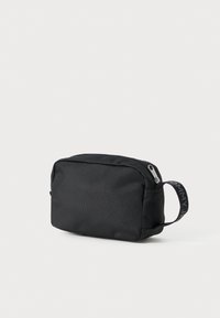 Fekete szövet toalett táska, téglalap alakú, cipzáros záródással és oldalsó fogantyúval, kontrasztos logóval.