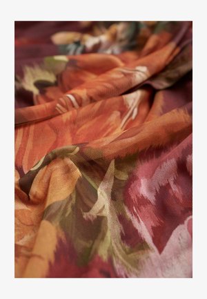 Gelaagd textiel met een bloemmotief in warme tinten van oranje, rood en groen, gedrapeerd om het vloeiende ontwerp te tonen.