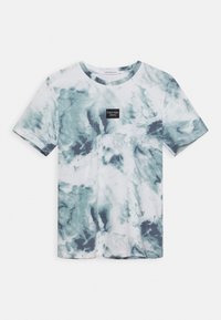 Camiseta de manga corta con cuello redondo, con un patrón de tie-dye azul y blanco y pequeño logo negro de Calvin Klein Jeans centrado en el pecho.