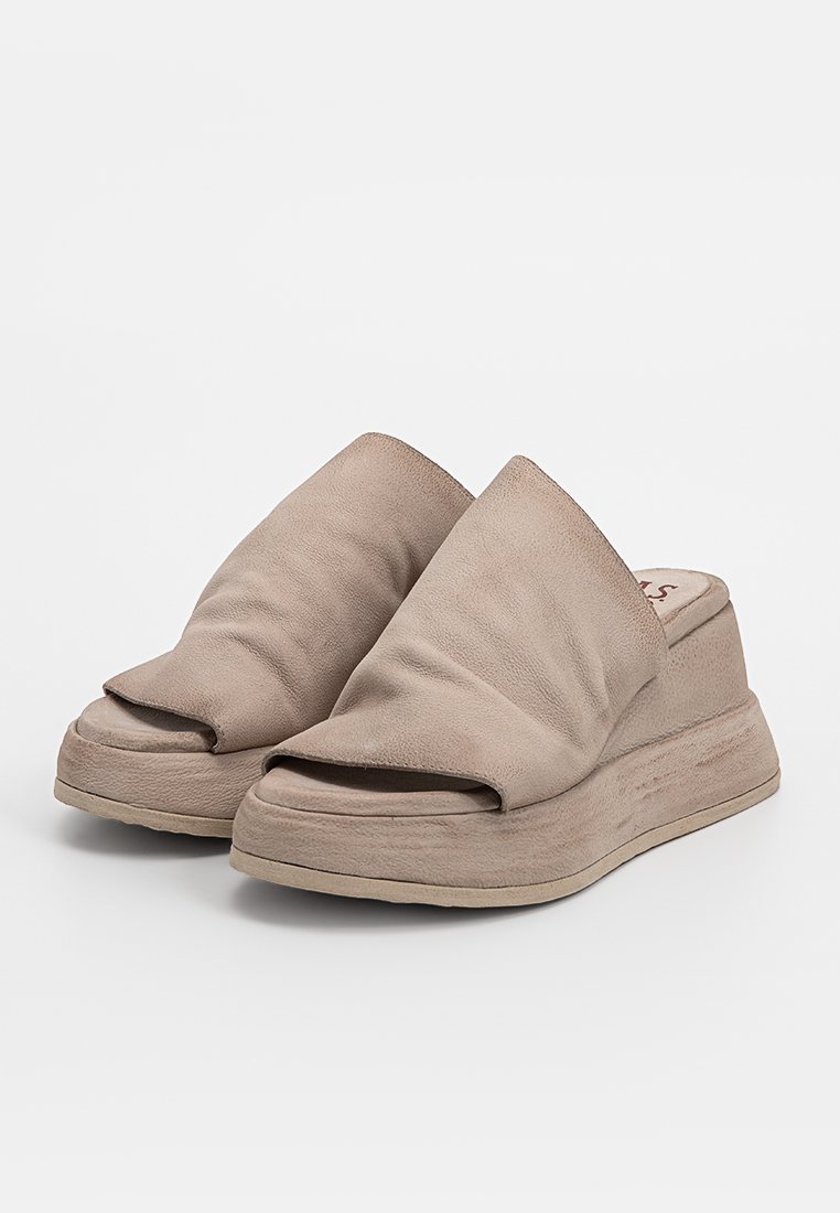 Beżowe buty typu slip-on z miękką skórzaną cholewką, otwartym noskiem i grubą platformą. Posiadają lekko pomarszczoną teksturę na powierzchni.