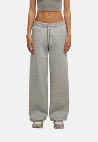 Pantaloni da tuta grigi chiari a gamba larga realizzati in morbida miscela di cotone, caratterizzati da una vita elastica con cordino e tasche laterali.