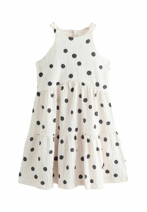 Weißes ärmelloses Sommerkleid mit schwarzen Polka-Dots, gestuftem Rock und dünnen Schulterriemen, die zu Schleifen gebunden sind.