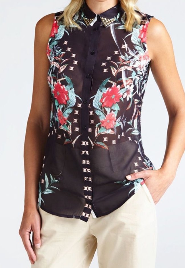 Blusa sin mangas negra con estampado floral en rojo y verde, cuello con tachuelas, cierre de botones en la parte delantera y dos bolsillos frontales.