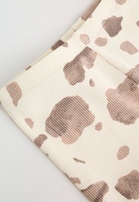 Gros plan sur un tissu côtelé avec des taches irrégulières beige et marron ressemblant à un motif imprimé vache.