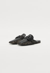 Chaussures noires en cuir à enfiler avec des détails en dentelle sur les côtés, design à bout pointu et un grand accent de boucle sur le dessus.