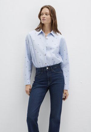 Light blue button-up shirt with small embroidered patterns; long sleeves, collar; paired with dark blue high-waisted jeans.