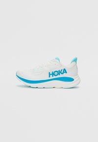 Chaussure de sport blanche avec un accent bleu et le logo "HOKA". Elle présente une semelle rembourrée, un dessus en mesh, un embout arrondi et des détails texturés.