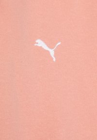 Svetloružové bavlnené tričko s bielou vyšitou logom Puma v skáčucej póze, hladká textúra s priliehavým strihom.