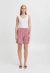 Shorts floreali in rosa e verde, realizzati in tessuto leggero con vita elastica. Abbinati a una canotta bianca semplice e sandali neri.