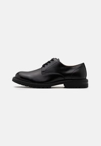 Chaussure habillée en cuir noir, avec un bout arrondi, un design à lacets, des détails de couture subtils et une semelle en caoutchouc texturée pour une meilleure adhérence.