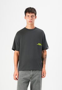 Black short-sleeve t-shirt made of cotton with a round neck, featuring a small yellow logo on the chest and a relaxed fit.