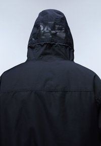 Chaqueta impermeable negra con capucha, con un detalle de logo mate en la parte posterior y un acabado suave y texturizado. Ideal para uso al aire libre.