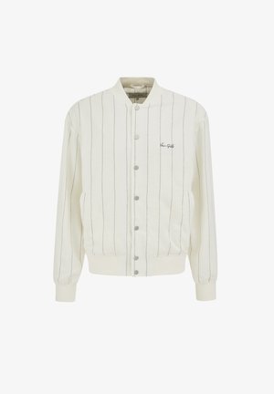 Valge bomber jakk koos peente vertikaalsete mustade triipudega, ees klõpskinnitustega, soonikvarrukatega ja vasakul rinnal tekstiga "Van Gils".