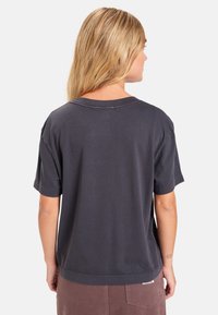 Mørkegrå T-shirt med kort ærme, afslappet pasform, rund halsudskæring og synlige sømme. Stoffet ser blødt ud med en glat tekstur.
