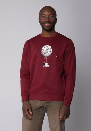 Burgundy sweatshirt with crew neck and long sleeves featuring a graphic of an astronaut holding a moon-shaped balloon against a grey background.