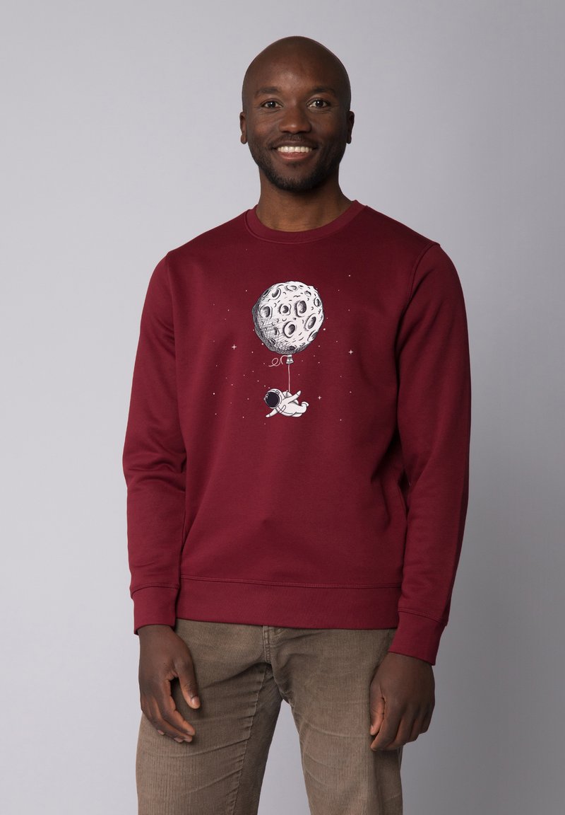 Sweatshirt bordeaux avec col rond et manches longues, ornée d'un graphisme d'astronaute tenant un ballon en forme de lune sur un fond gris.