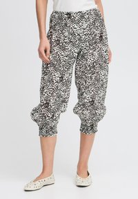 Pantaloni cropped a scacchi in bianco e nero con vita elastica e polsini arricciati. Il tessuto è leggero e presenta una finitura testurizzata.