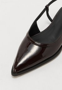 Spiss tå, mørkebrun patentlæder slingback-sko med en glat, blank finish og en tynn ankelrem.