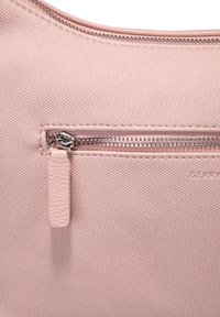 Borsa di stoffa rosa chiaro con superficie texurizzata, tasca con zip argentata e un piccolo tirante in pelle per la zip.