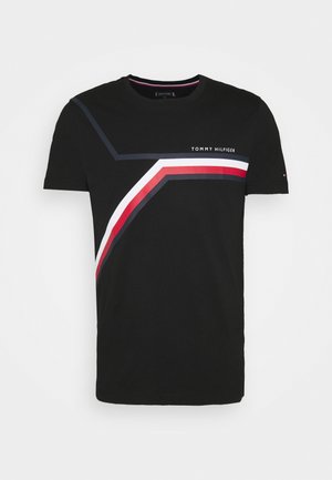 Camiseta negra de Tommy Hilfiger con rayas en ángulo en blanco, rojo y azul oscuro en el pecho y texto del logo en el lado derecho.