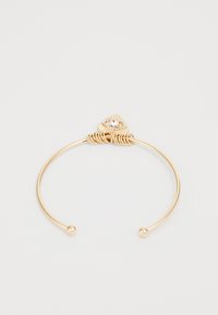 Pulsera de oro con un diseño de triángulo en la parte superior, centrada por una piedra brillante, con alambres retorcidos y extremos redondeados.