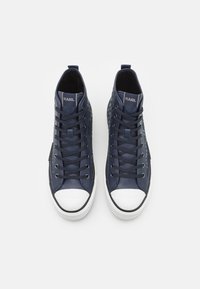 Mornarsko visoke teniske s teksturiranim vzorcem, belim kapicom na prstih in vezalkami. Imajo logotip na ježku in gladke akente.