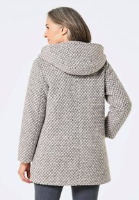 Grau gewebter Mantel mit Kapuze, der ein strukturiertes Muster und lange Ärmel aufweist. Der Saum ist leicht abgerundet und bietet eine lockere Passform.